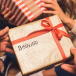 A man gives his partner a Christmas present with the Binnari handbags logo inscribed on it.