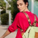 Modelo paseando en bicicleta con la mochila de moda para mujer Mina de la colección primavera-verano Getaway de Binnari.