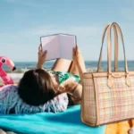 Bolso shopper Cala, uno de los bolsos de mujer de verano que son tendencia en 2024 sobre una toalla en la playa con una mujer leyendo.